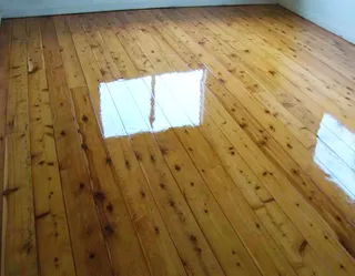 After: Newly refinished wooden floor with a mirror-like shine and window reflections