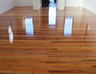 After: Glossy restored hardwood floor with a rich, even finish