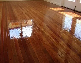After: Professionally polished timber floor with a deep, reflective sheen