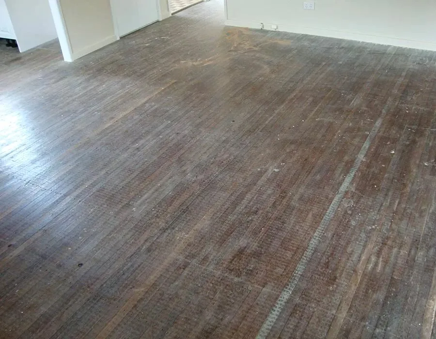 Before: Worn, stained timber floorboards before sanding and refinishing