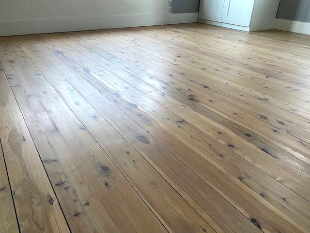 Whitewashed timber floor in an empty room with white cabinetry